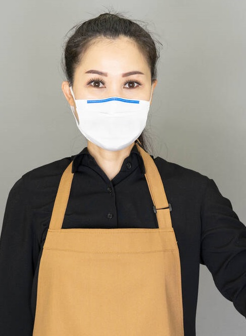 Asian Woman housewife in brown apron wore face mask in hands  bottle spray for washing windows isolated on gray background,housework and household concept.