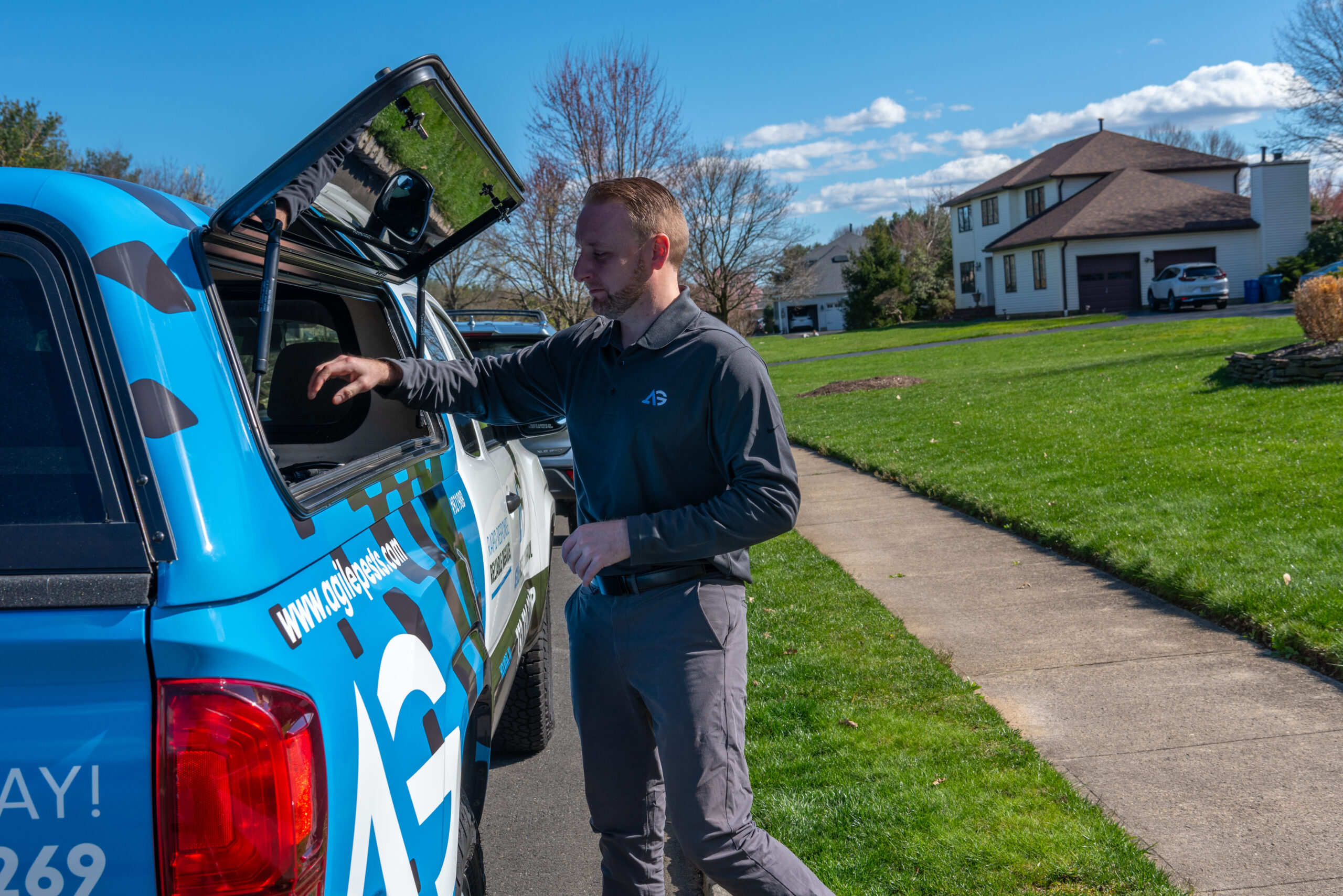 Agile Pest Control technician performing a pest control service in Tinton Falls, NJ, inspecting and treating the exterior of a home.