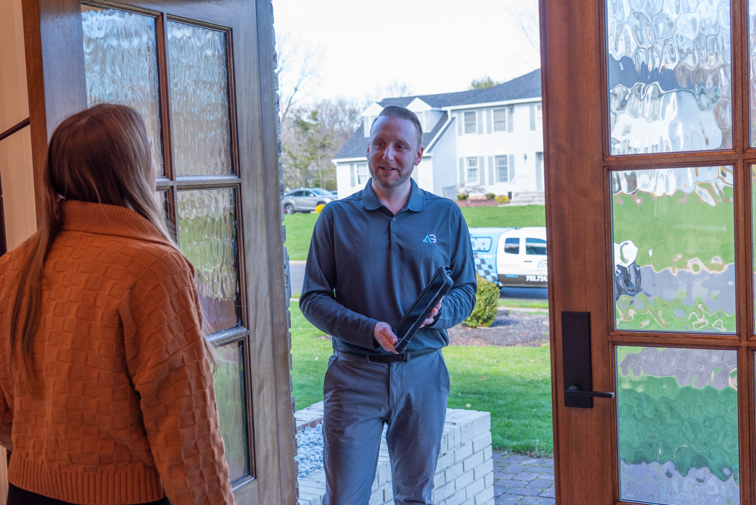 Agile Pest Control technician entering a homeowner's home in Hazlet, NJ, ready to review a pest control proposal with the client.