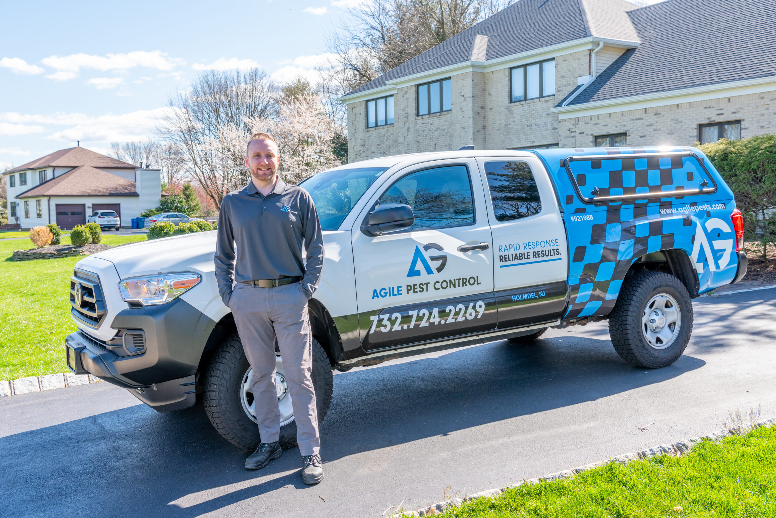 Agile Pest Control technician performing a pest control service at a home in Freehold, NJ, applying treatment around the property to ensure effective pest management.