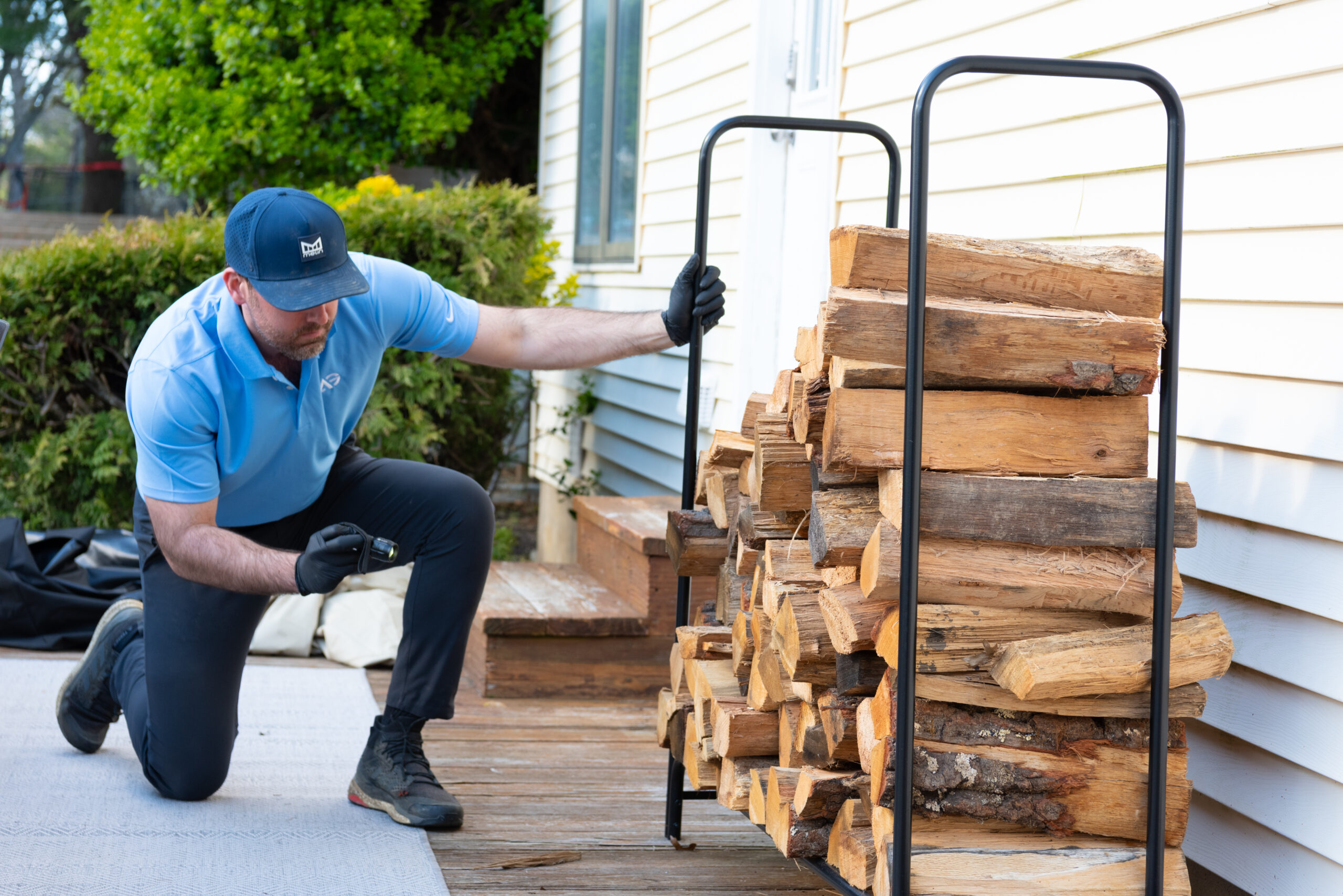 Agile Pest Control technician inspecting firewood outside a home in Eatontown, NJ.