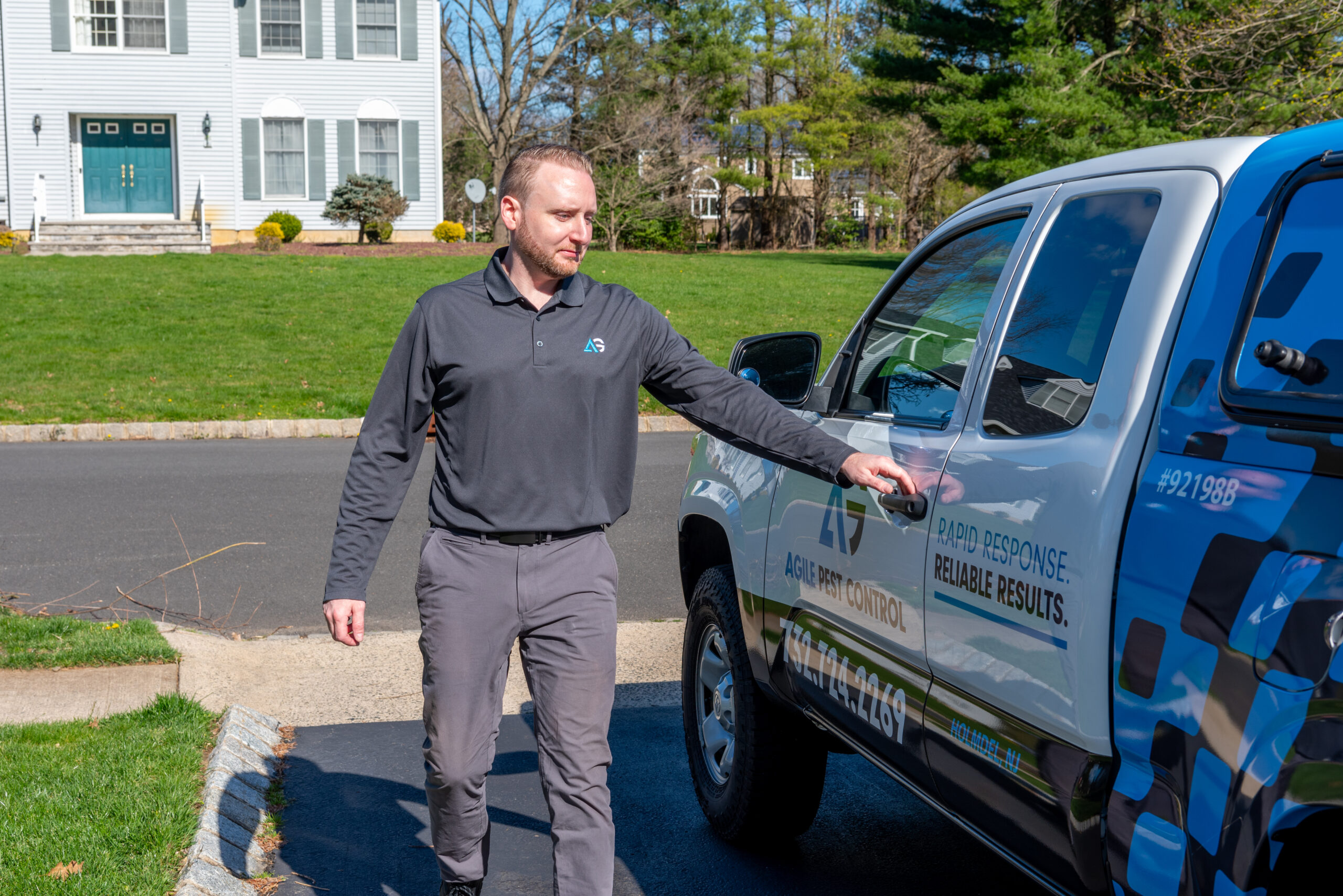 Agile Pest Control technician conducting a pest control service at a residential property in Long Branch, NJ, wearing protective gear and using specialized equipment to ensure effective pest management.