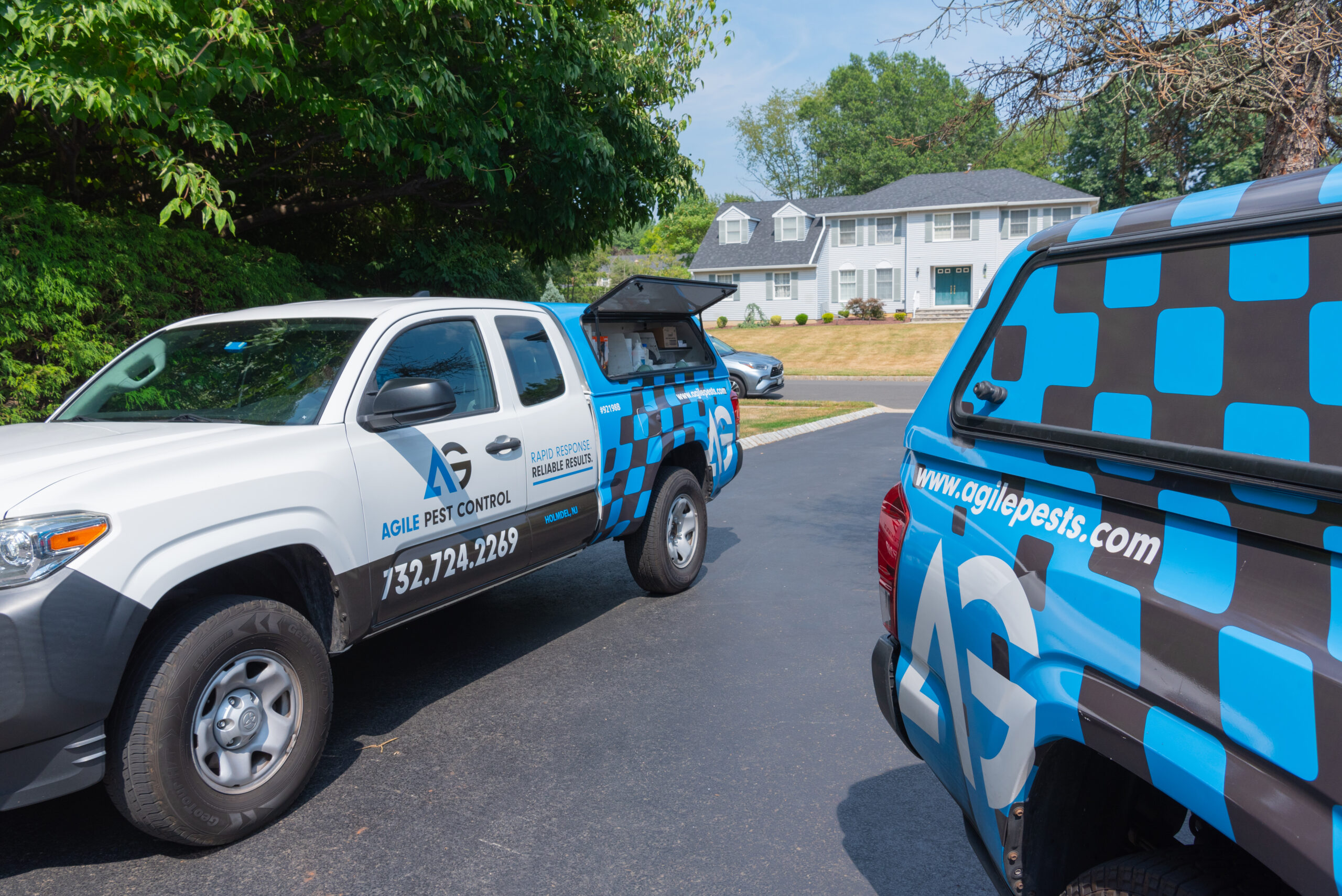 Agile Pest Control truck parked in a residential driveway in Howell, NJ, for a bed bug control service, with a technician preparing equipment to inspect and treat the home for bed bug infestations.