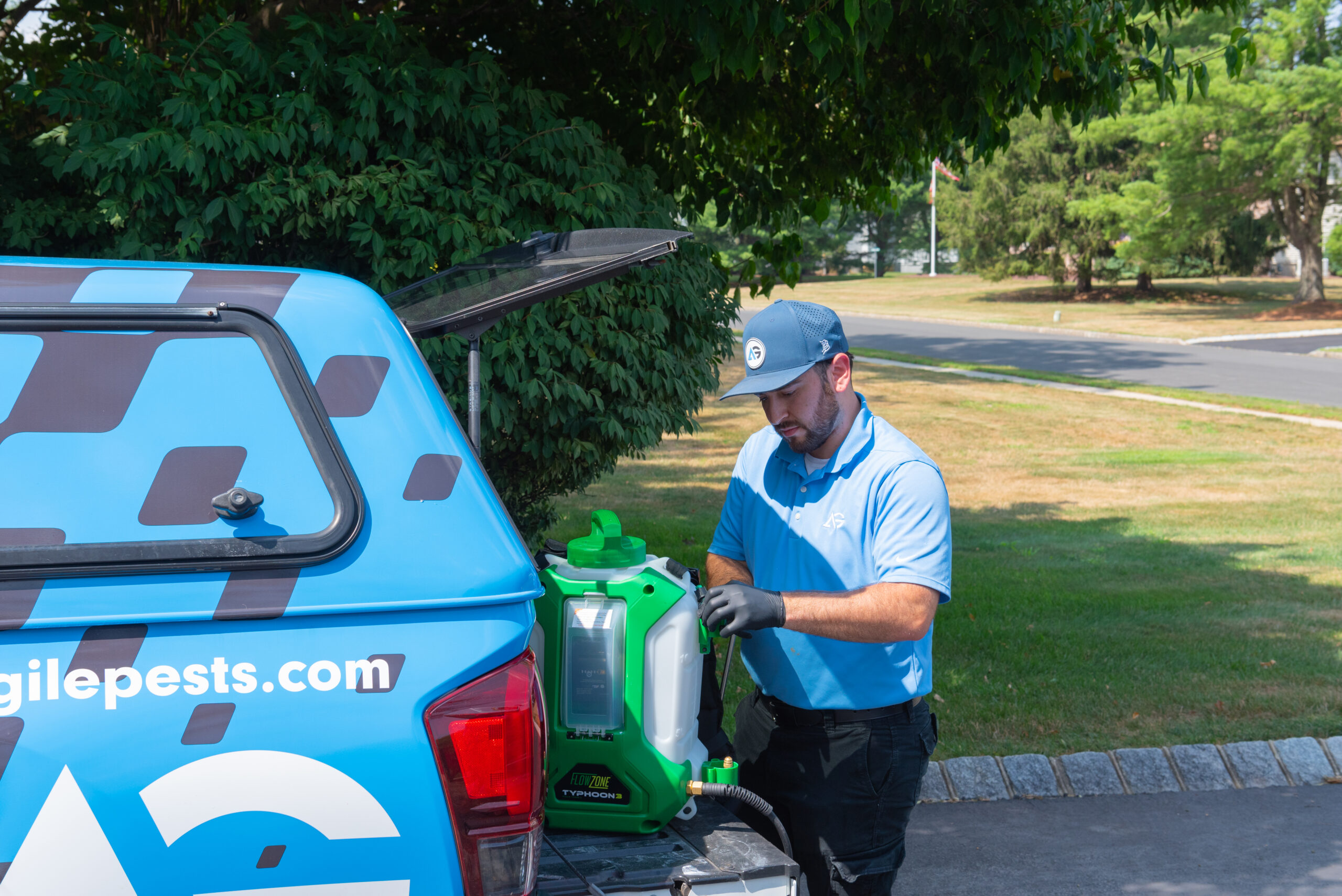 Agile Pest Control technician preparing equipment for an exterior carpenter ant control service at a home in Holmdel, NJ, ensuring thorough pest treatment around the property.