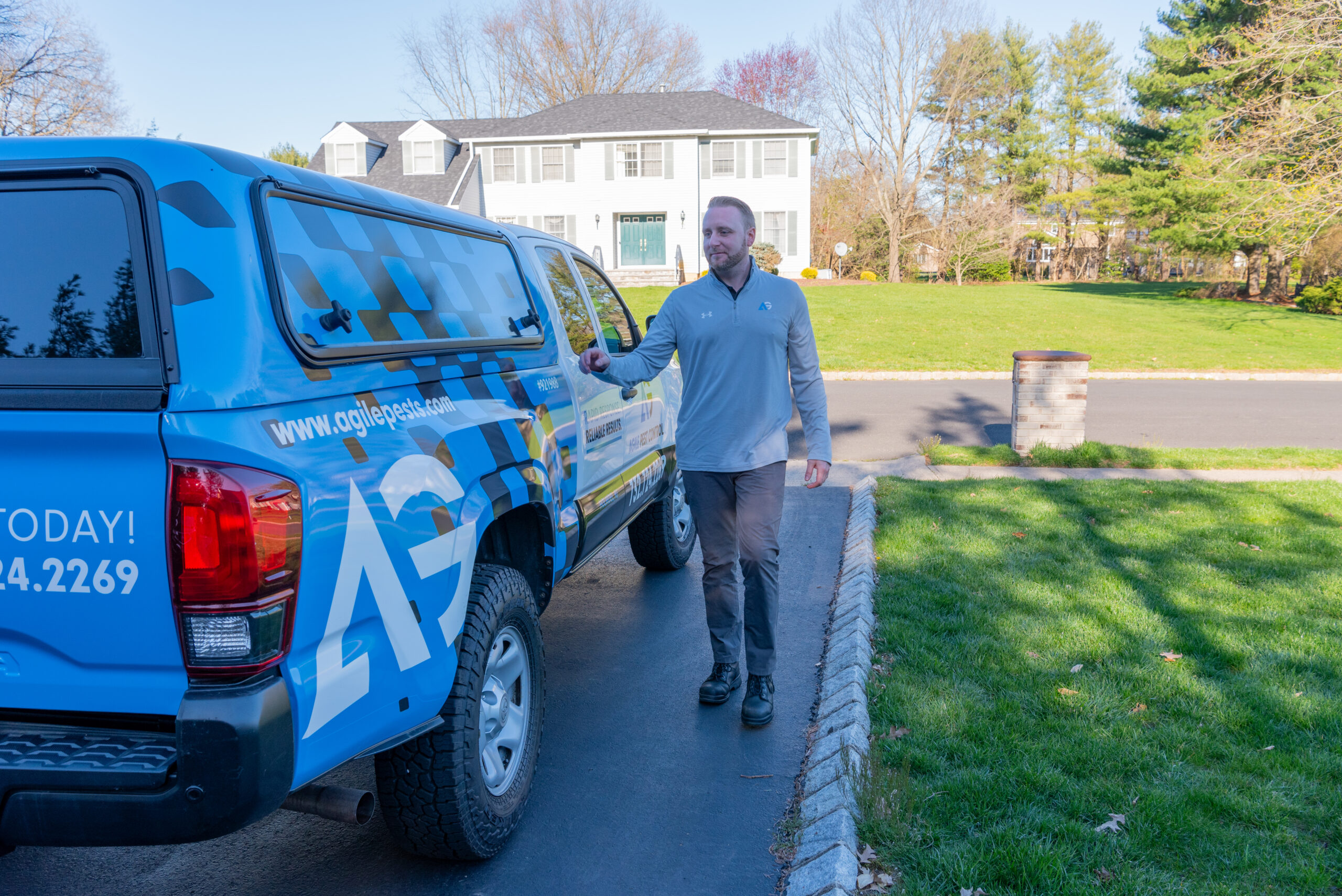 Agile Pest Control technician arriving at a residential driveway in Holmdel, NJ, prepared for a carpenter ant control inspection with professional equipment and expertise.