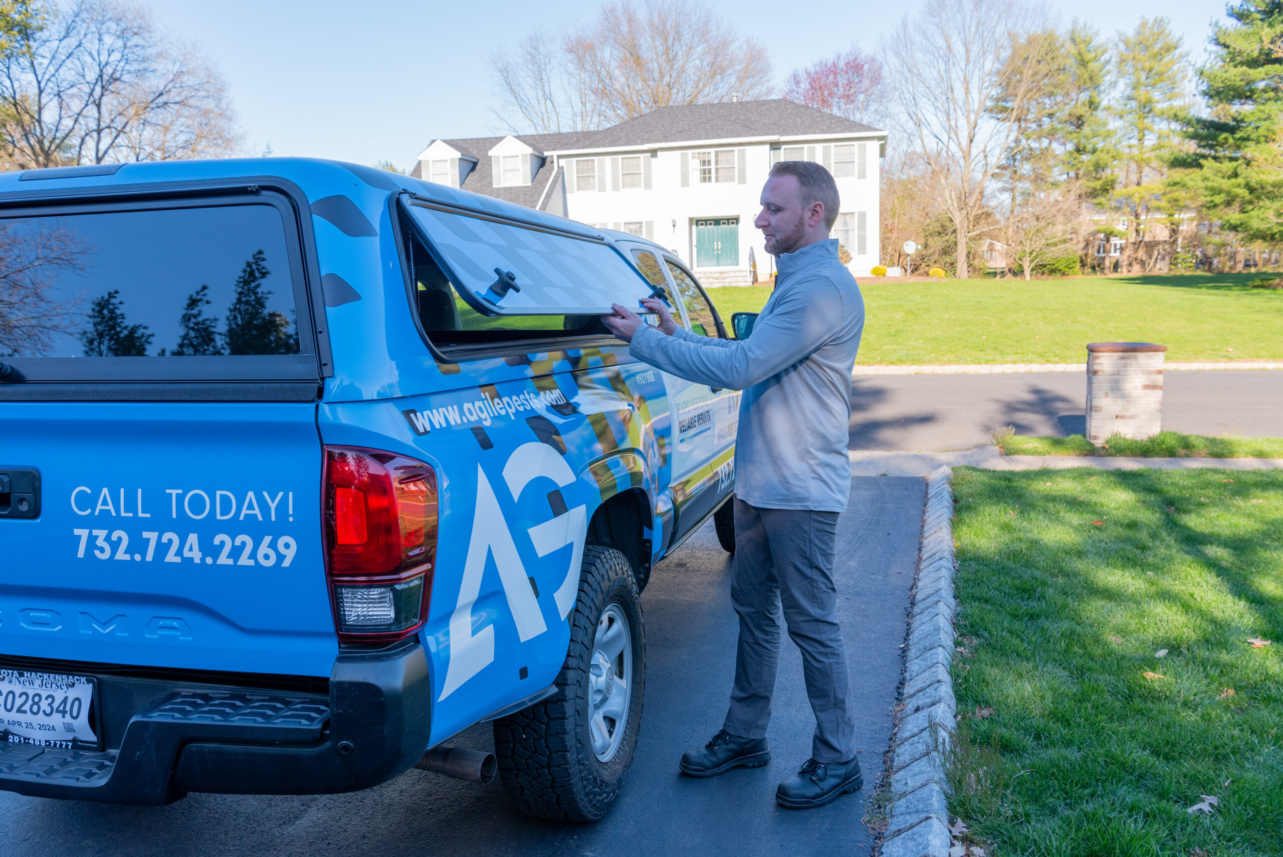 Agile Pest Control technician in Manalapan NJ, preparing equipment for a thorough bed bug inspection, standing near a residential home, ready to assess and treat potential infestation areas.